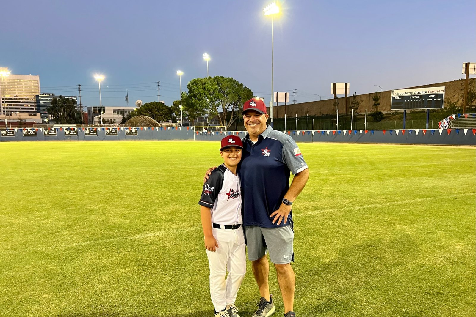 Jeff Schwartz and his son on an
       empty outfield at dusk, stadium lights on, after a game in Los Angeles.